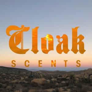 May include: A sunset sky with the word "Cloak" in a large, stylized font, with the word "SCENTS" below it. The sky is a gradient of orange, pink, and purple.