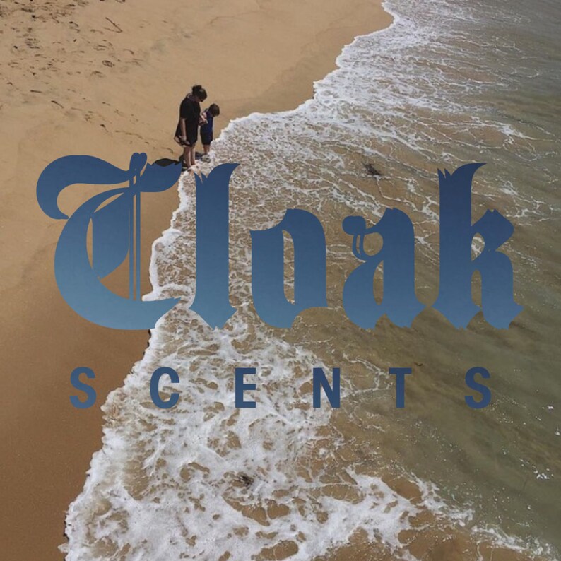 May include: A blue and white graphic design with the text "Cloak Scents" on a beach background with a woman and child standing in the surf.