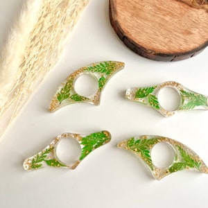 May include: Four clear resin bookmark holders with gold flecks and pressed green leaves.