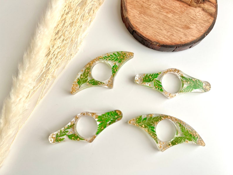 May include: Four clear resin bookmark holders with gold flecks and pressed green leaves.