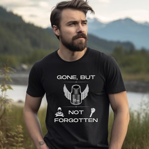 May include: Black t-shirt with a white graphic design that says "Gone, But Not Forgotten". The graphic features a wrench with wings and the text "10 mm".
