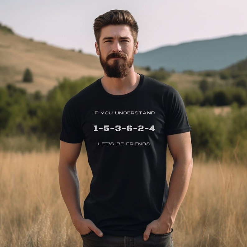 May include: A black t-shirt with white text that reads "If you understand 1-5-3-6-2-4 Let's be friends". The shirt is being worn by a person with a beard standing in a field.