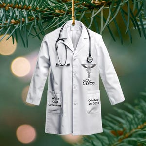 May include: White coat ornament with a stethoscope, a medical symbol, and the name "Alice." The coat has pockets and the text "White Coat Ceremony" and "October 20, 2025."