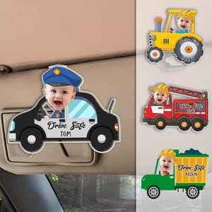 May include: Three car-shaped photo holders with a child's face in each. The cars are a police car, a fire truck, and a dump truck. Each car has the text "Drive Safe" and a name below it. The names are Tom, Tom, and Kelvin.