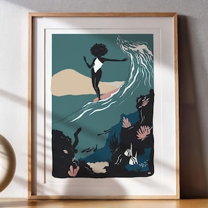 Könnte beinhalten: Gerahmter Kunstdruck mit einem Surfer auf einer Welle. Das Kunstwerk zeigt eine Person in einem weißen Badeanzug, die eine türkisfarbene Welle surft, vor einem dunklen Hintergrund mit Korallenakzenten. Der Druck befindet sich auf einem Holzschrank mit dekorativen Gegenständen.