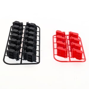 Op de afbeelding: Twee sets kleine plastic componenten. De ene set is zwart en de andere rood. Elke set is gerangschikt op een zwart of rood plastic frame. De componenten lijken klein, rechthoekig en hebben een geribbeld ontwerp.