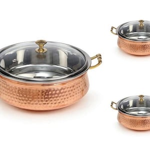 Puede incluir: Tres platos de servir de cobre con tapas. Los platos son martillados y tienen un acabado de cobre brillante. Las tapas son de vidrio transparente y tienen asas de latón.