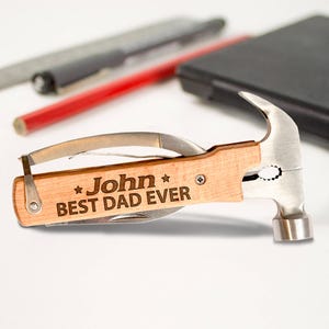 May include: A multi-tool with a hammer head, a wooden handle, and a blade. The handle is engraved with the text "John Best Dad Ever".