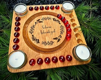 May include: Wooden Advent calendar with the words "Schöne Adventszeit" engraved in a wreath design. The calendar features four candle holders with white candles, red glass beads, and a natural wood finish.