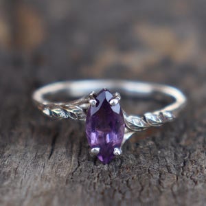 May include: A silver ring with a purple amethyst gemstone set in a twisted band.