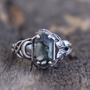 May include: A silver ring with a green moss agate gemstone set in a leaf design.