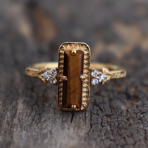 May include: Gold ring with a rectangular tiger's eye stone and small clear stones on the band.