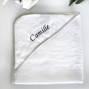 Könnte beinhalten: Weißes Kapuzenhandtuch mit grauem Tupfenrand und dem Namen "Camille" in Schwarz gestickt.