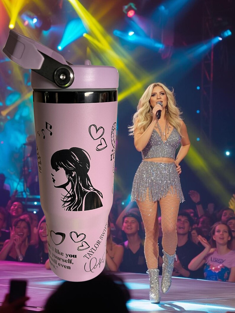 May include: A light pink insulated tumbler with a black and white silhouette of a woman, musical notes, and hearts. The tumbler has the text "Taylor Swift" and a signature. The lid is light purple.