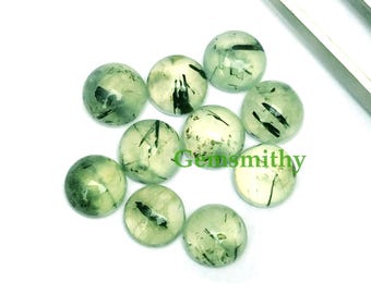 May include: A collection of ten round, green gemstone cabochons with black inclusions. The cabochons are smooth and polished.