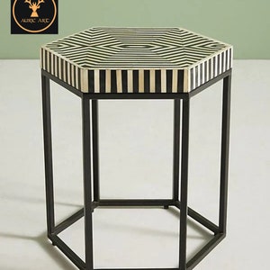 May include: A hexagonal side table with a black and white bone inlay top and a black metal frame.