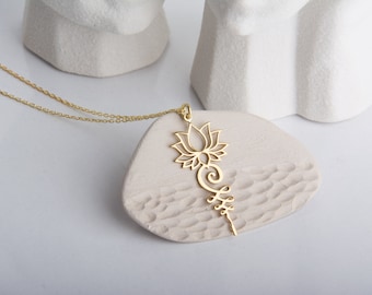 May include: A gold-toned necklace with a delicate chain and a pendant featuring a stylized lotus flower design.