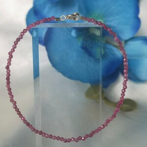May include: A delicate pink gemstone bracelet with a silver clasp. The bracelet is made of small, round beads and is strung on a thin silver chain.