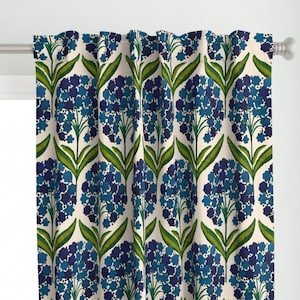 May include: Curtain with a floral pattern. The design features blue hydrangea flowers and green leaves on a cream backdrop. The curtain hangs from a white rod. The design brings a touch of nature to any room.