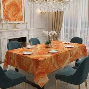 Puede incluir: Una mesa de comedor con un mantel con estampado abstracto naranja y dorado. La mesa está puesta con platos blancos, vasos y cubiertos. Sillas color turquesa rodean la mesa y una lámpara de araña cuelga encima.