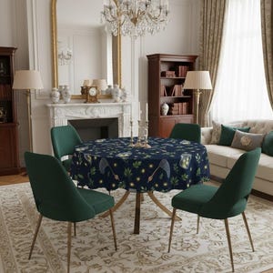 Puede incluir: Una mesa de comedor redonda con un mantel azul marino con un diseño caprichoso de luciérnagas, hojas y redes. Cuatro sillas de terciopelo verde con patas doradas rodean la mesa. Una lámpara de araña cuelga encima.