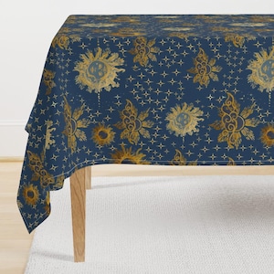 Puede incluir: Un mantel azul marino con un patrón repetido de soles y estrellas doradas. Los soles tienen diseños intrincados y son de varios tamaños. Las estrellas son pequeñas y están dispersas por la tela, creando un tema celestial.