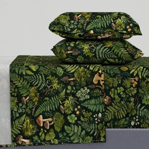 Puede incluir: Juego de cama verde oscuro con un estampado botánico de helechos, setas y otros elementos forestales. El juego incluye dos fundas de almohada y una sábana bajera, todas con un diseño detallado inspirado en la naturaleza. La estética general es una mezcla de tonos naturales y terrosos.