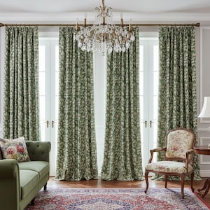 May include: A living room with green floral curtains, a green sofa with a floral pillow, and a patterned rug. A vintage-style chair with floral upholstery and a small side table with a lamp are also present. A crystal chandelier hangs from the ceiling.