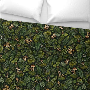 May include: A dark green and brown duvet cover featuring a detailed pattern of various ferns, mushrooms, and other forest foliage. The design includes a variety of green shades and brown mushroom caps, creating a natural, woodland theme. The duvet is placed on a white bed.