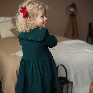 Girl wearing collared cotton dress, with long sleeves, dark green color
