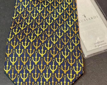 May include: A navy blue silk tie with a repeating pattern of gold anchors. The tie comes with a small white card with the text "R.USSARDI" and "certificato di garanzia".