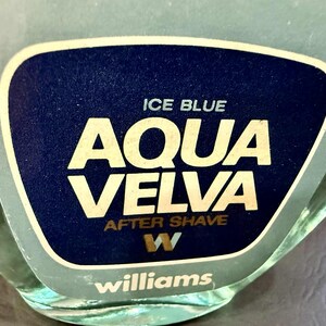 Puede incluir: Primer plano de un frasco de loci&oacute;n para despu&eacute;s del afeitado Aqua Velva. La etiqueta es azul oscuro con las palabras "ICE BLUE" y "AQUA VELVA" en blanco, y "AFTER SHAVE" en dorado. La marca "Williams" est&aacute; en la parte inferior.