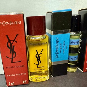 May include: An assortment of Yves Saint Laurent miniature perfume bottles. The bottles are in their original boxes, featuring the YSL logo and text. The bottles contain a yellow liquid and are labeled "Pour Homme" and "Eau de Toilette".