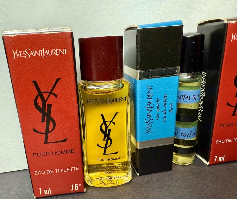 May include: An assortment of Yves Saint Laurent miniature perfume bottles. The bottles are in their original boxes, featuring the YSL logo and text. The bottles contain a yellow liquid and are labeled "Pour Homme" and "Eau de Toilette".