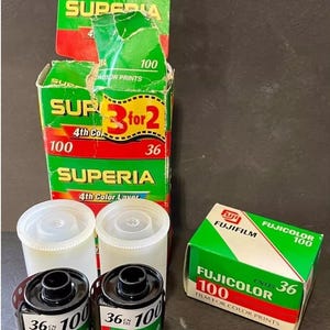 May include: Three rolls of 36 exposure 100 speed Fujicolor film. Two rolls are in clear plastic containers and one roll is in a green and red box. The box has the text "Fujicolor 100" and "Film for Color Prints".