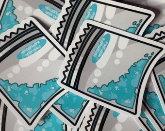 May include: A stack of blue and white stickers with the text "Heisenberg approved" in a white oval on a blue background. The stickers are shaped like a small bag with a black outline.