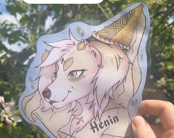 May include: Printed and laminated badge featuring a stylized canine character with a light brown and pink color scheme. The badge has a light blue background with decorative elements and the name "Henin". Text at the top reads "FURRY CON BADGE COMISSIONS".