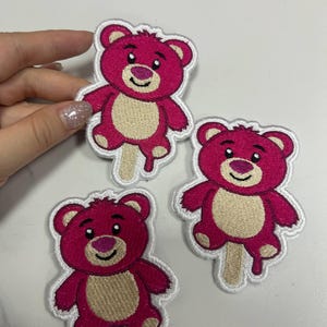 K&ouml;nnte beinhalten: Gestickte Aufn&auml;her mit einem rosa Teddyb&auml;r-Design mit hellbraunem Bauch und einem Eisstiel. Die Aufn&auml;her haben einen wei&szlig;en Rand und eignen sich f&uuml;r Kleidung oder Accessoires.