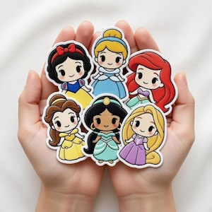 Op de afbeelding: Een verzameling van zeven cartoon prinsessen patches, elk met een uniek ontwerp. De prinsessen zijn Sneeuwwitje, Assepoester, Ariel, Belle, Jasmine en Rapunzel. De patches hebben een witte rand.