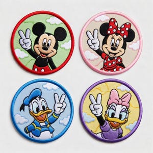 Può includere: Quattro toppe ricamate con i personaggi Disney Topolino, Minnie, Paperino e Paperina. Ogni toppa è circolare con un bordo colorato e un personaggio che fa il segno della pace. Topolino è rosso, Minnie rosa, Paperino blu e Paperina viola.