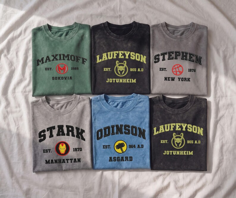 May include: Six crew neck t-shirts in various colors, each featuring a character name, a circular icon, an establishment year, and a location. The shirts display names including Maximoff, Laufeyson, Stephen, Stark, and Odinson with associated graphics.