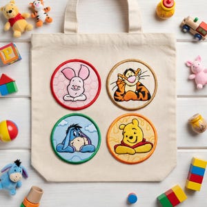 May include: A cream tote bag with four embroidered circular patches featuring characters from Winnie the Pooh: Piglet, Tigger, Eeyore, and Winnie the Pooh. Children's toys are scattered around the bag.