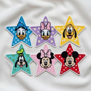 May include: A collection of six star-shaped embroidered patches featuring Disney characters. Each patch showcases a different character: Donald Duck, Daisy Duck, Pluto, Goofy, Minnie Mouse, and Mickey Mouse. The patches are in various colours with polka dot and floral patterns.
