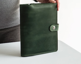 May include: A dark green leather bound journal with a silver button closure.