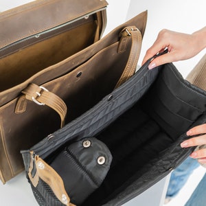 Pu&ograve; includere: Una borsa tote in pelle marrone con una cerniera nera e un interno nero e marrone. La borsa &egrave; aperta e l'interno &egrave; visibile. La borsa ha una tasca con cerniera nera all'interno.
