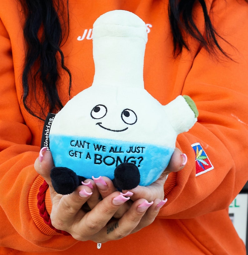 K&ouml;nnte beinhalten: Ein blaues und wei&szlig;es Pl&uuml;schspielzeug in Form einer Bong mit einem l&auml;chelnden Gesicht und dem Text "Can't we all just get a bong?"