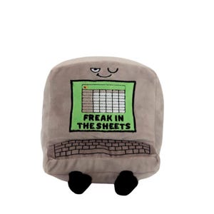 May include: A gray plush toy shaped like a computer with a winking face and the text "Freak in the sheets" on the screen. The toy has a green screen with a spreadsheet and a gray keyboard.