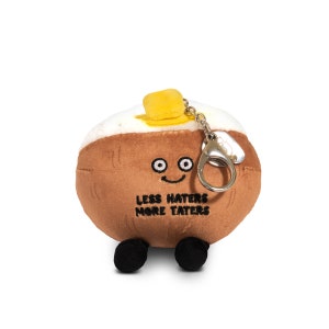 May include: A brown plush potato keychain with a yellow butter pat on top. The potato has a smiling face and the text "Less Haters More Taters" is embroidered on the front.