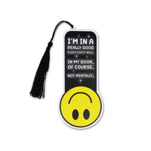 May include: A black and white bookmark with a black tassel. The bookmark has the text "I'M IN A REALLY GOOD PLACE RIGHT NOW. IN MY BOOK, OF COURSE. NOT MENTALLY." A yellow smiley face is at the bottom.