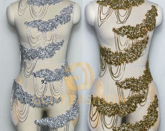 Peut inclure: Deux mannequins portent des chaînes de corps décoratives avec des strass et des perles. Les chaînes sont argentées et dorées et sont disposées en cascade. Les mannequins portent un tissu de couleur chair sous les chaînes.